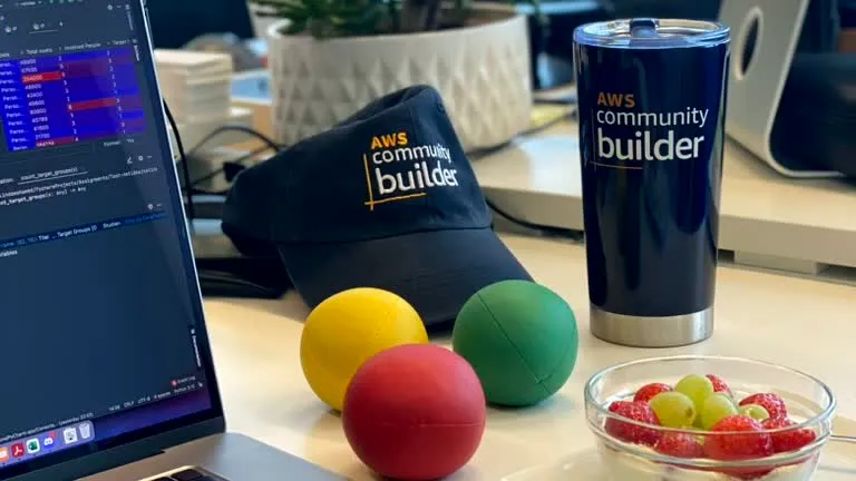 A desk with an AWS Community Builder hat, a coffee tumbler, and juggling balls resting nearby