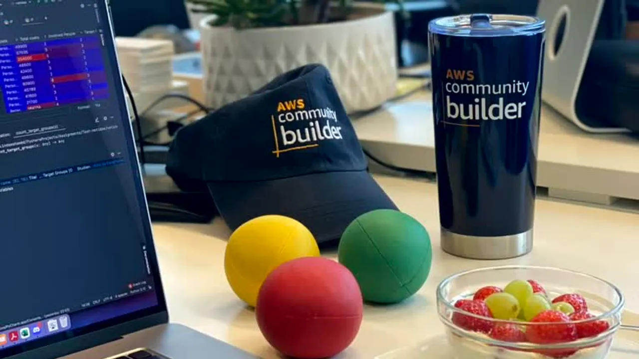 A desk with an AWS Community Builder hat, a coffee tumbler, and juggling balls resting nearby