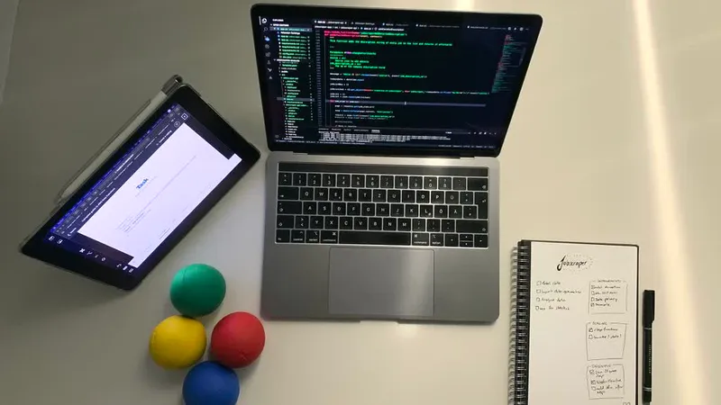 Overhead view of a desk showing a laptop with code on screen and juggling balls resting nearby