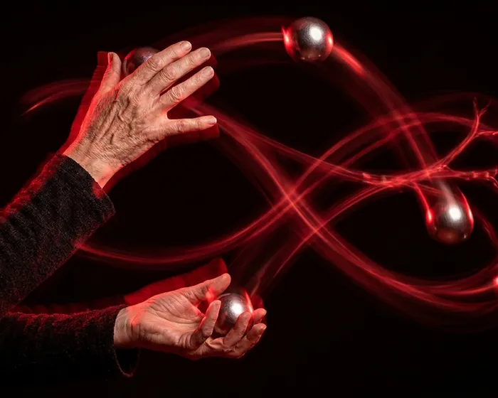 Weathered elderly hands juggling with red infinity light trails