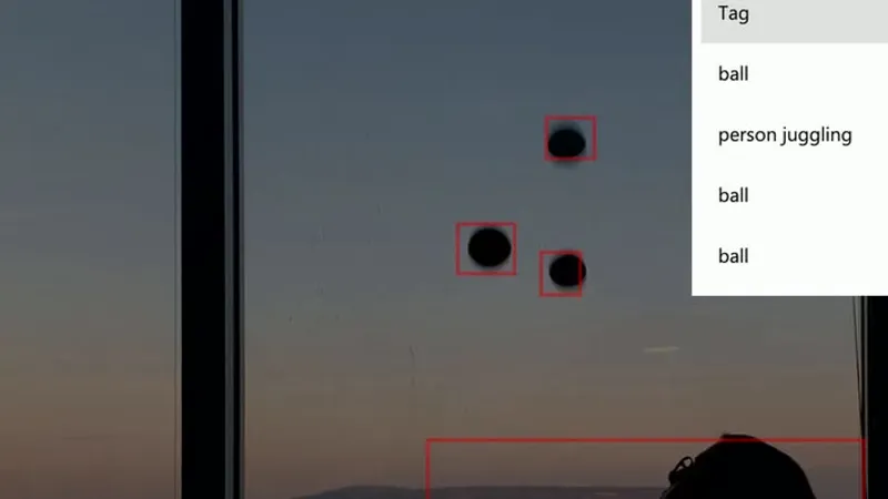 A juggler mid-throw in front of a window, with Azure Custom Vision bounding boxes visible around the body and ball in the detection overlay