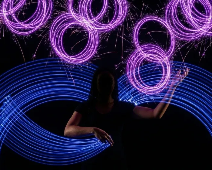 Woman surrounded by rings at scale - large blue arcs below, purple rings multiplying above